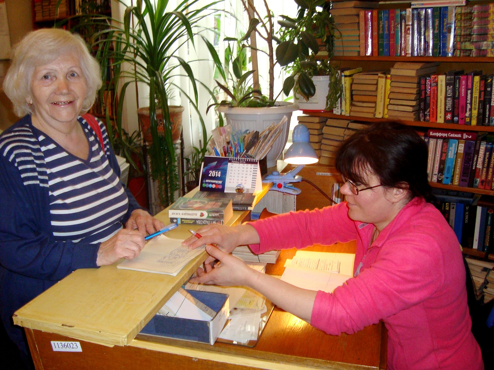 бібліотекар Валентина Гонтаренко обслуговує одного з найстаріших читачів бібліотеки Курлянд Ларису Іванівну